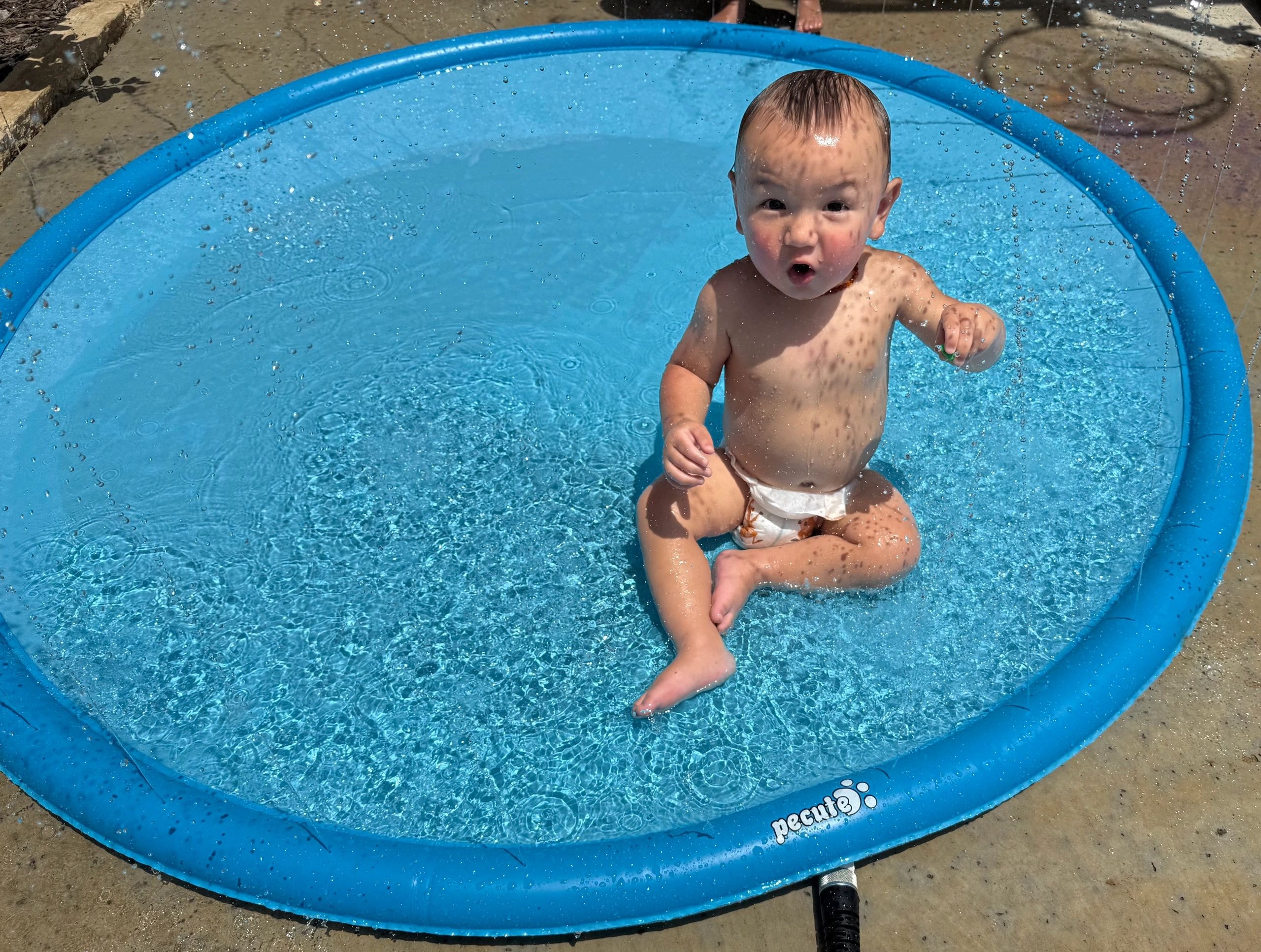 Toddler splashing in kiddie pool